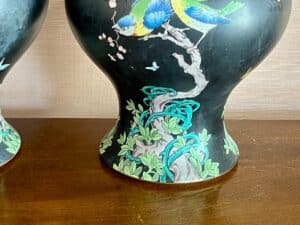 Decorative vase with colorful bird and floral design, set on a wooden surface.