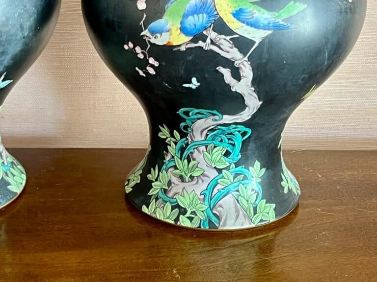 Decorative vase with colorful bird and floral design, set on a wooden surface.