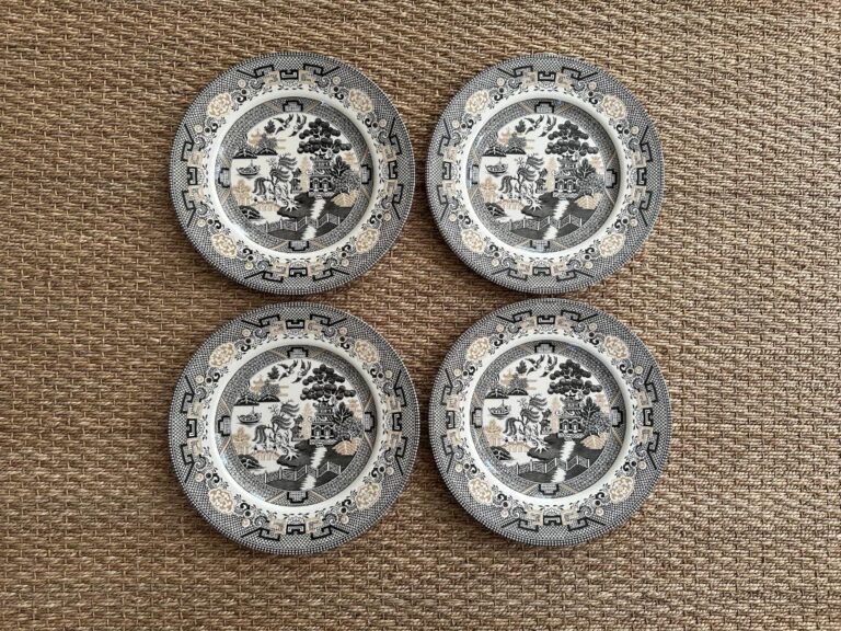 Four decorative blue and white porcelain plates with intricate designs on a textured woven surface.