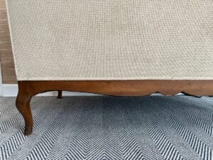 A Chenille Upholstered Settee on a chevron-patterned rug against a textured wall.