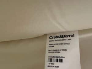 Close-up of a Crate & Barrel label on a cream-colored Sedona divided hamper liner, made in India.