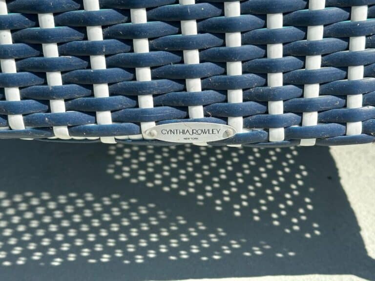 Close-up of a blue wicker chair with a "Cynthia Rowley New York" metal label attached.