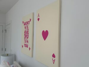 Two wall art pieces: an ace of hearts card and a playing card with "Lucky You" in red text.
