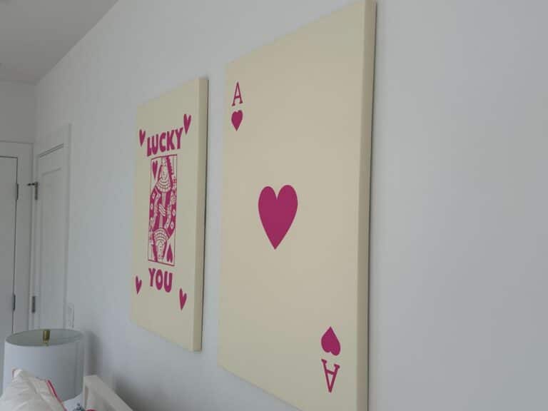 Two wall art pieces: an ace of hearts card and a playing card with "Lucky You" in red text.