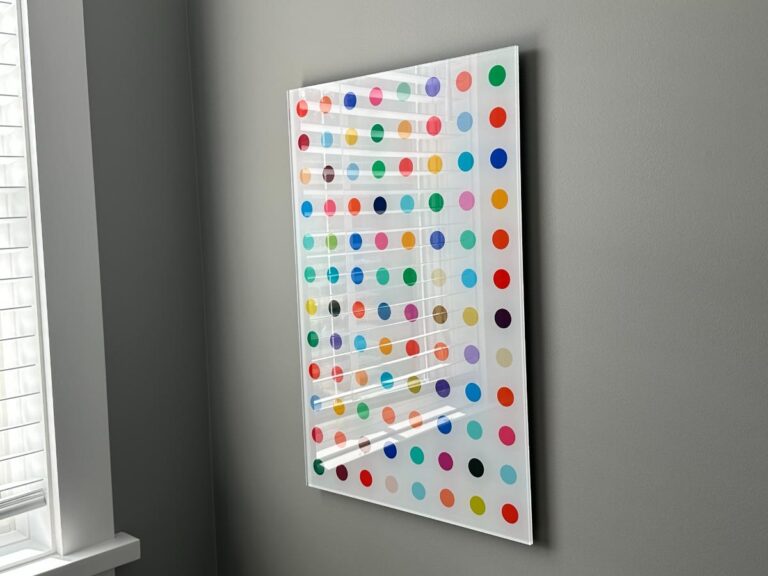 A colorful dot pattern artwork hangs on a gray wall near a window with white blinds.