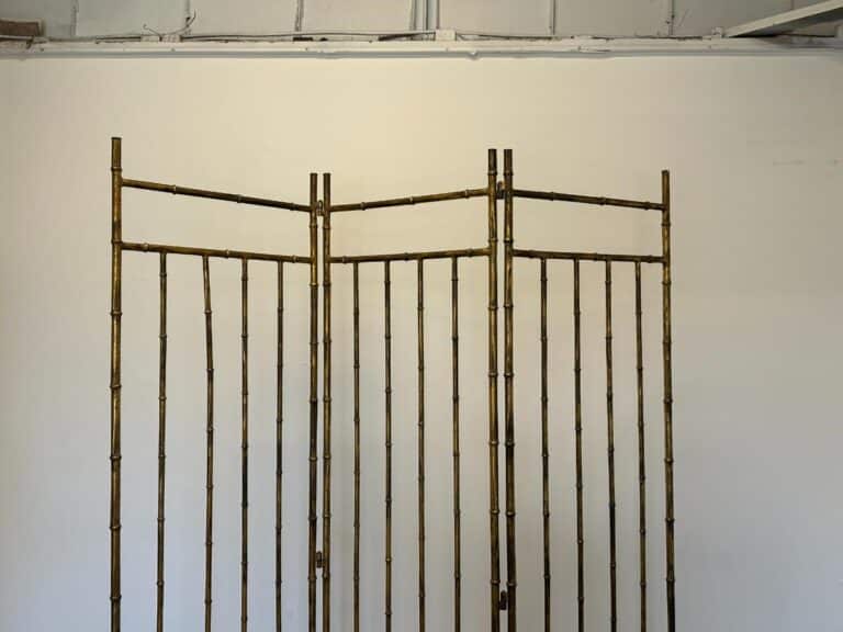 A Maison Bagues Gilt Bamboo Metal Folding Screen with three panels stands against a plain white wall.