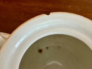 White ceramic bowl with a small chip on the rim, placed on a wooden surface.