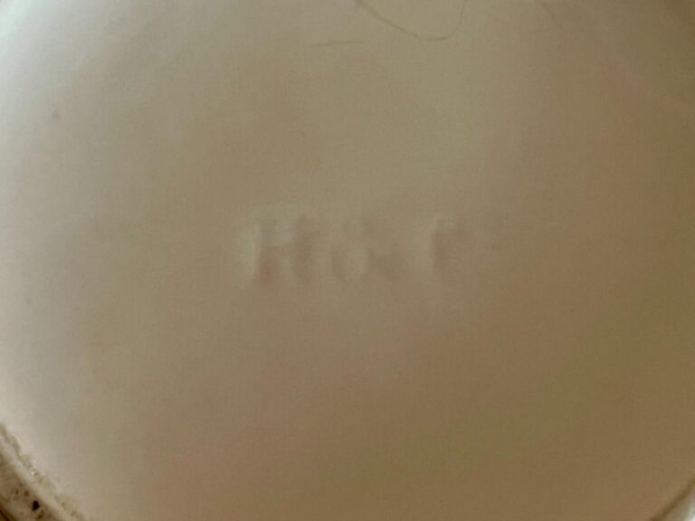 Faded impression with letters "M & C" on a beige surface.
