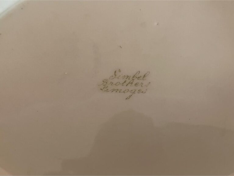 Faded text reading "Dimbel Brothers Limoges" on a beige surface.