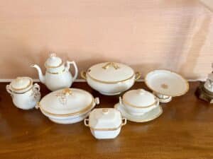 A set of elegant white porcelain dishware with gold accents displayed on a wooden surface.