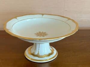 Elegant white and gold decorative pedestal bowl on a wooden surface.