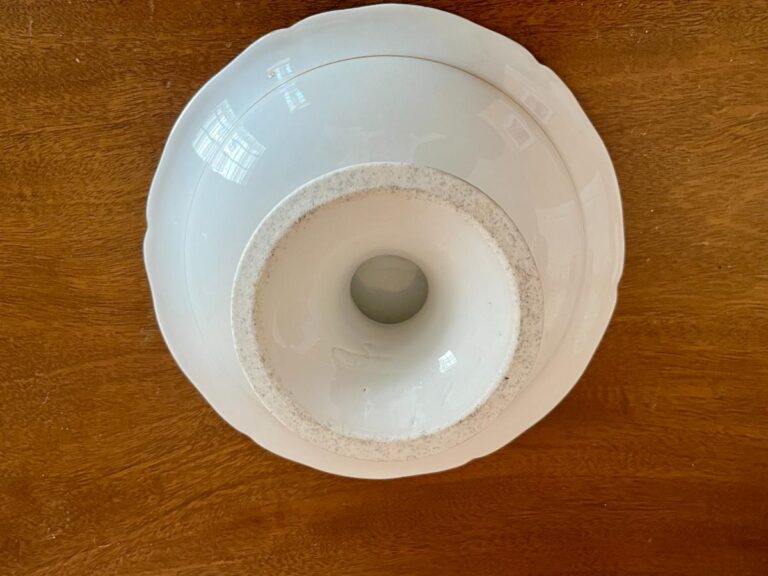 A white ceramic bowl inverted on a wooden surface, forming a funnel shape.