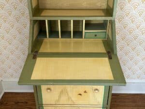 Vintage wooden secretary desk with fold-out writing surface, small cubbyholes, drawer, and bird motif on the front.