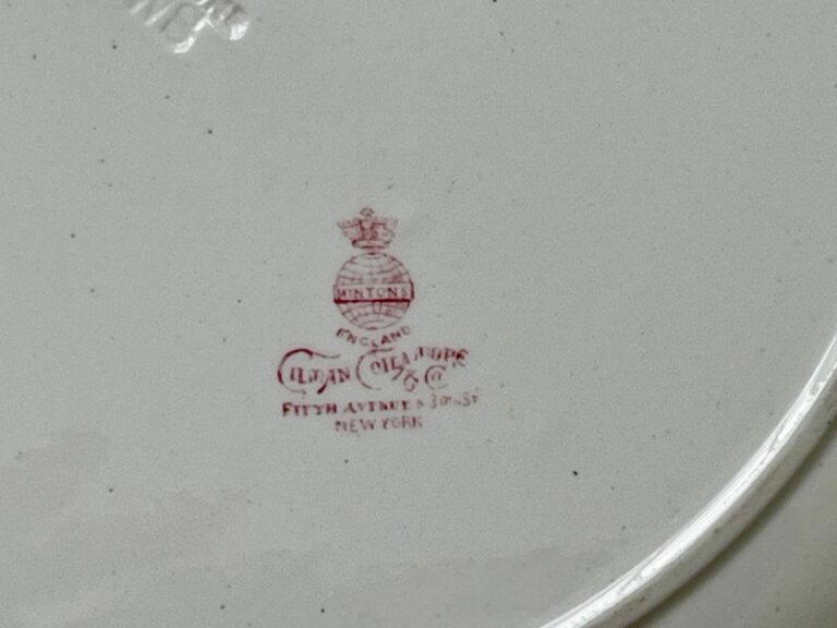 Red pottery mark with crown and text on a white ceramic surface.