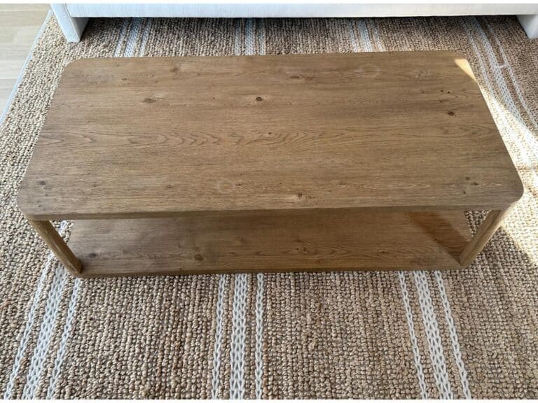 Rectangular wooden coffee table with a lower shelf, placed on a woven rug.