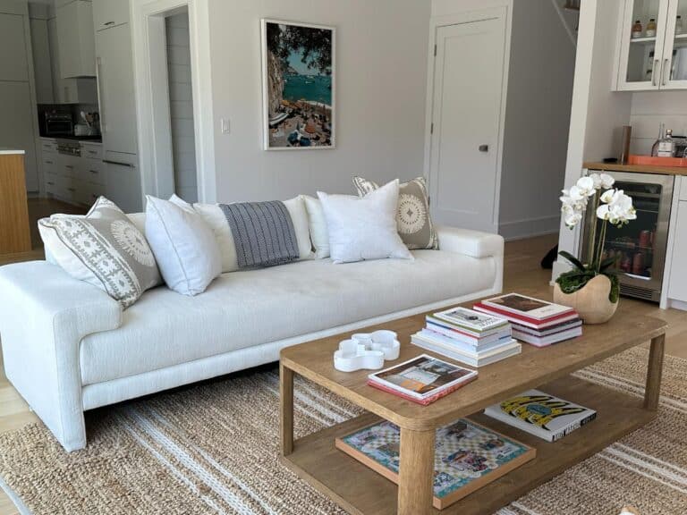 Modern living room with a white sofa, wooden coffee table with books, and neutral decor accents.