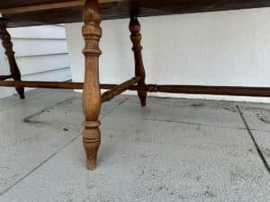 Wooden table legs on a textured, tiled surface. White wall in the background.