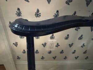 Blue corner chair with Cowtan & Tout seat in front of wallpaper showcasing a small floral pattern.