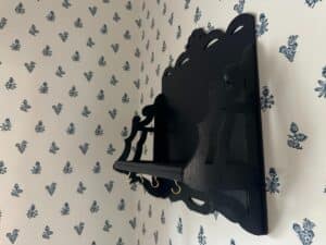 A Blue Wall Shelf / Bracket installed on a wall with black decorative features and blue floral-patterned wallpaper.