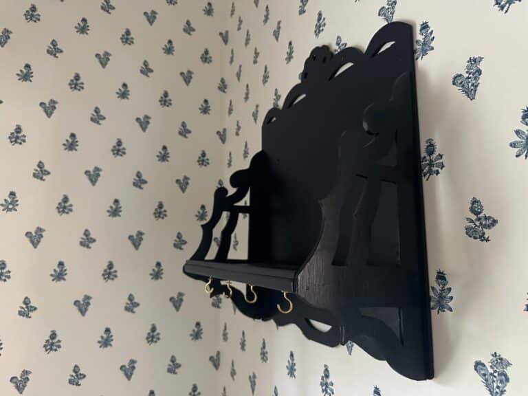 A Blue Wall Shelf / Bracket installed on a wall with black decorative features and blue floral-patterned wallpaper.