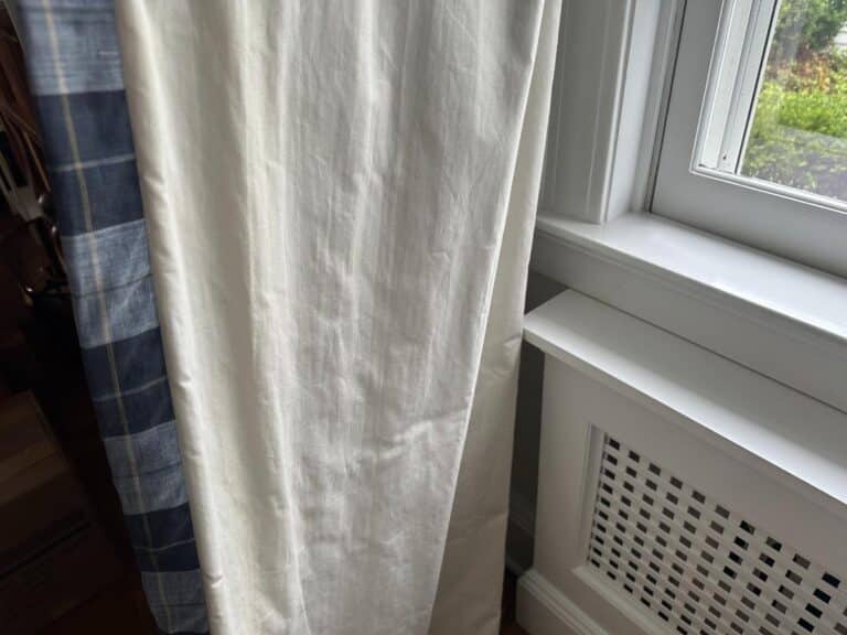 Close-up of Blue Stripe Panels, Set of 6, featuring light and dark stripes next to a white window frame with a hint of greenery beyond.