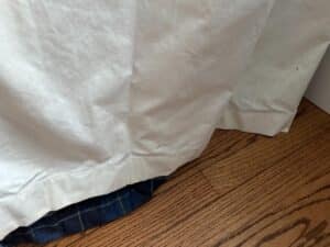 A white curtain hem gently touches the wooden floor, revealing a peek of the Blue Stripe Panels, Set of 6, underneath.