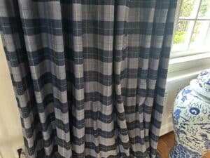 Blue stripe panels, set of 6, hang beside a decorative blue and white vase by a window.