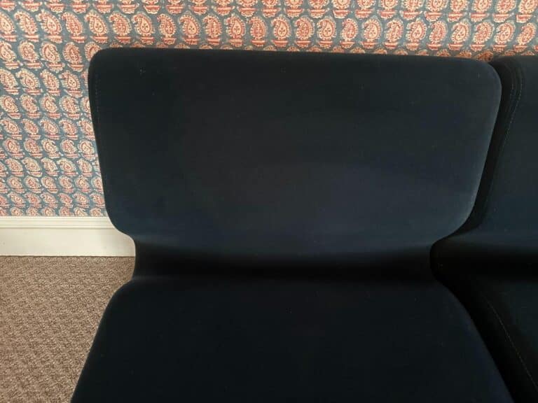 The Herman Miller Blue Sectional features a black cushioned seat set against stunning paisley-patterned wallpaper.