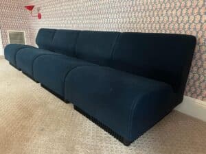 A Herman Miller Blue Sectional in a modern design sits against patterned wallpaper and a carpeted floor.