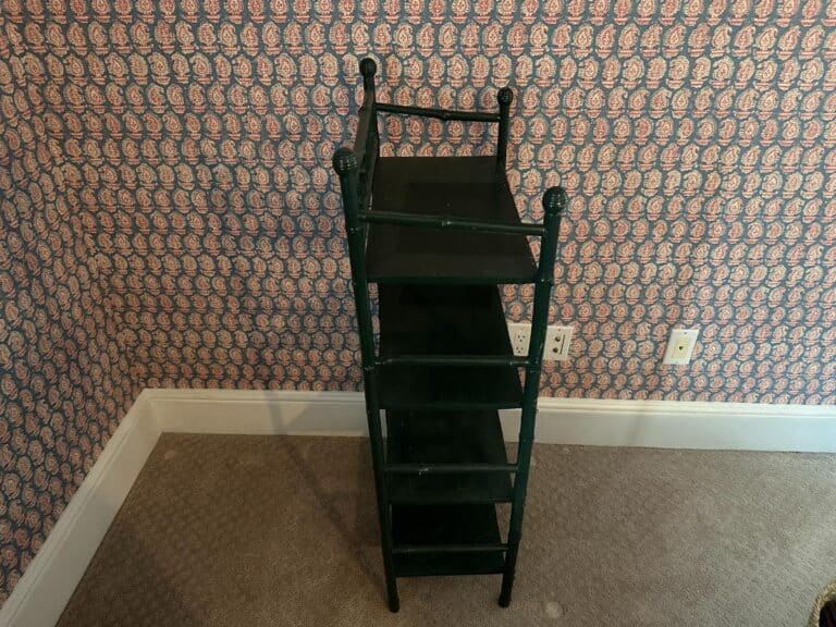 A compact green bamboo etagere is placed in a room with patterned wallpaper and beige carpet.