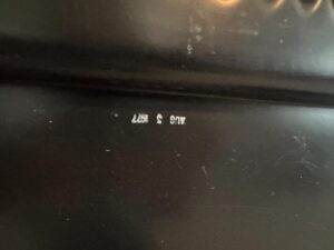 Close-up of a black surface with tiny white text "Herman Miller Blue Sectional" upside down.