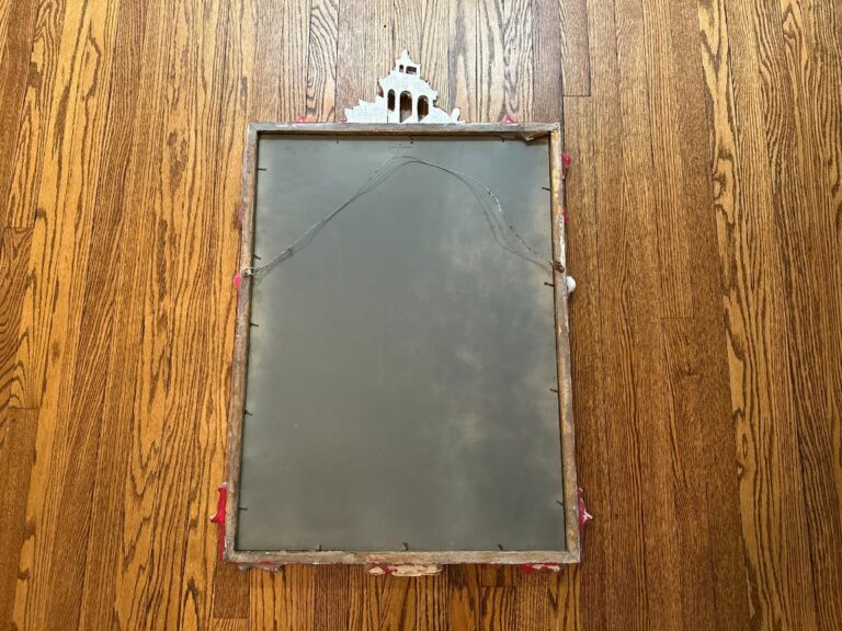 Back view of the Vintage Chinoiserie Mirror with decorative trim, lying on a wooden floor.