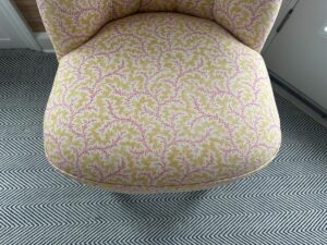 Petite Tufted Back Side Chair on Casters with ornate pink and yellow floral design sits on a black-and-white zigzag pattern carpet.