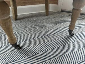 A Petite Tufted Back Side Chair on Casters with wooden legs is placed on a blue and white chevron-patterned rug.