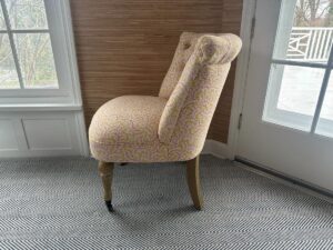 The Petite Tufted Back Side Chair on Casters sits in a room with chevron carpet, white paned windows, and a door.