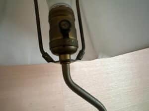 Close-up of a brass socket and stem beneath the shade of a Blanc De Chine Figural Lamp.