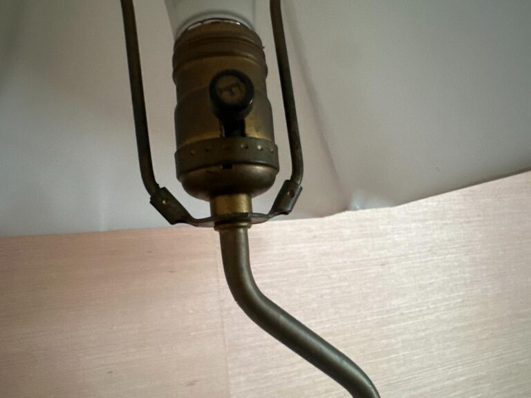 Close-up of a brass socket and stem beneath the shade of a Blanc De Chine Figural Lamp.