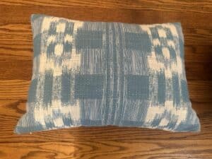 Sister Parish Mahalo Print Pillows, Pair featuring a blue and white pattern, rest on a wooden floor.