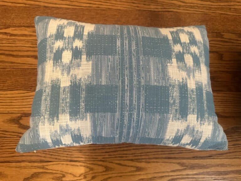 Sister Parish Mahalo Print Pillows, Pair featuring a blue and white pattern, rest on a wooden floor.