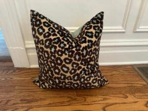 Cut Velvet Leopard Pillow on a wooden floor against a white wall.