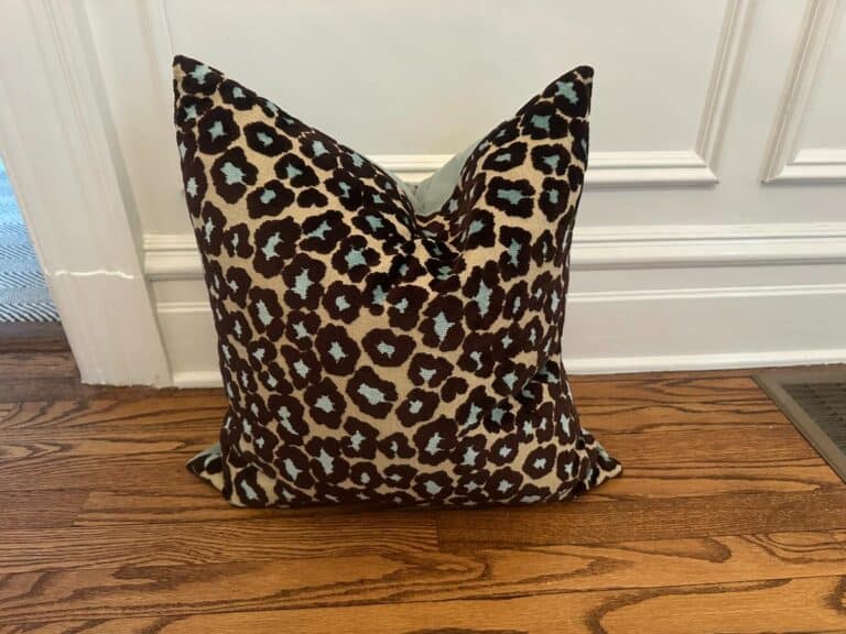 Cut Velvet Leopard Pillow on a wooden floor against a white wall.