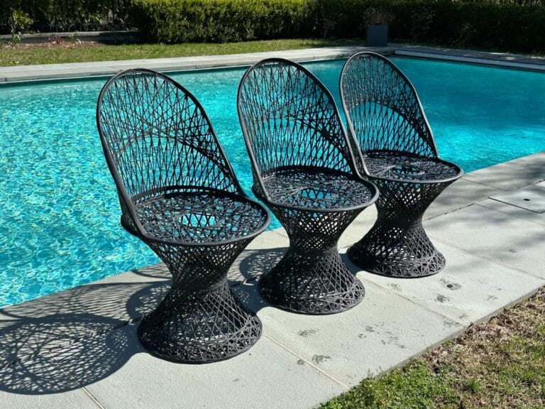 Three Vintage Spun Black Chairs beside a sparkling pool on a sunny day.