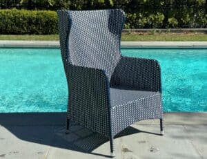 A Cynthia Rowley Blue & White Outdoor Chair decorates a poolside patio with clear blue water in the background.