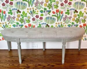 Demilune Tufted Bench set against vibrant floral wallpaper with a wooden floor.