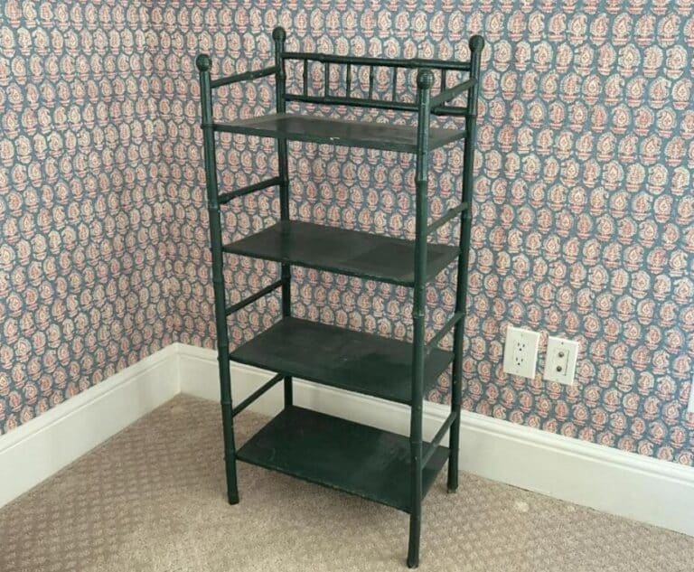 A Green Painted Bamboo Etagere with four shelves stands in a room featuring pink patterned wallpaper and a carpeted floor.