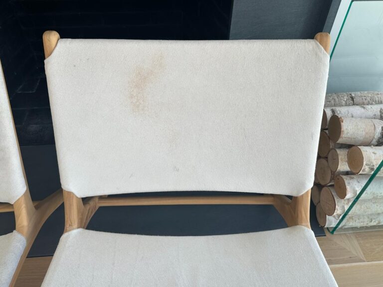 White fabric chair with a wooden frame, showing a brown stain on the upper left of the backrest.