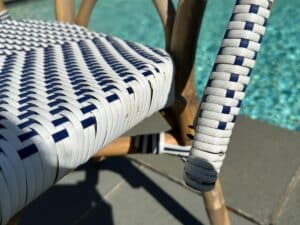 Close-up of a woven chair with white and blue patterns next to a pool.