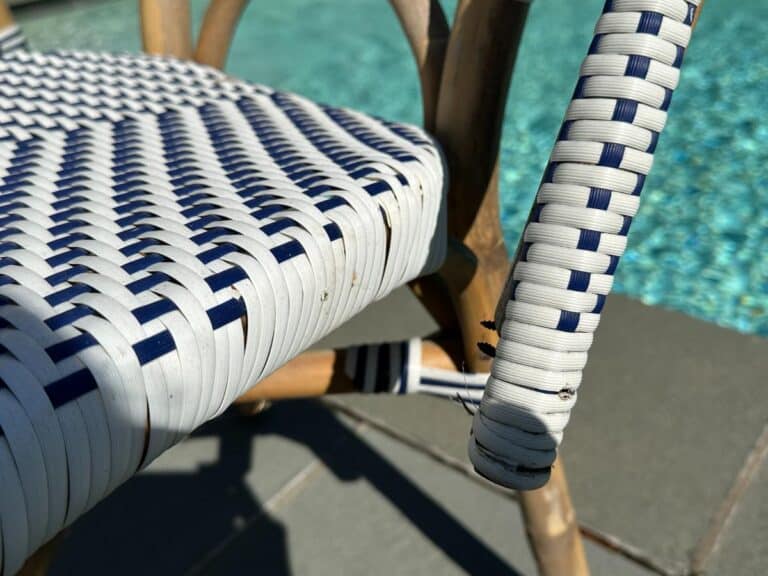 Close-up of a woven chair with white and blue patterns next to a pool.