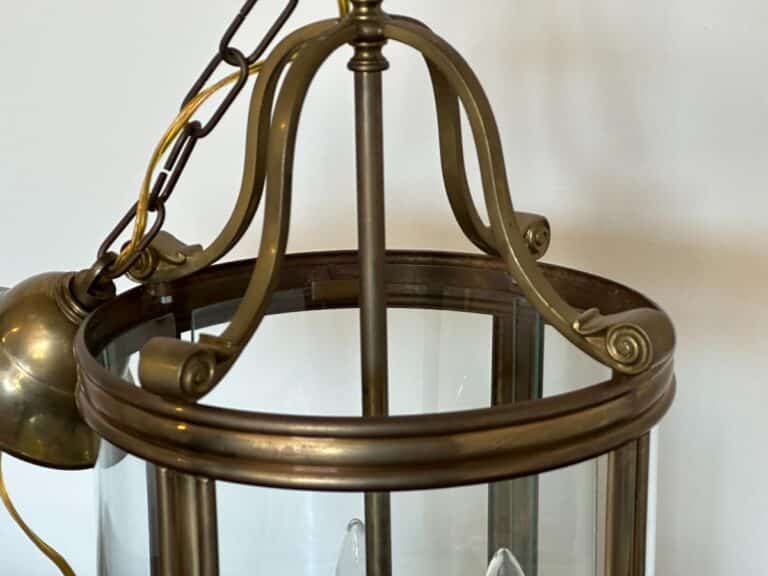 Close-up of a brass and glass hanging lantern with curved metal supports and a chain for suspension.