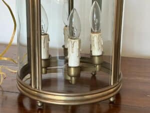 Close-up of a vintage brass and glass lantern with candle-shaped electric bulbs inside.